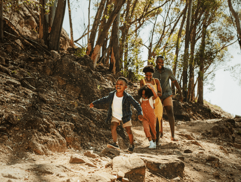 Two adults and two kids running through a hiking trail